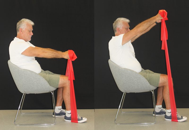 Man performing global upper limb flexion-extension exercise with a band
