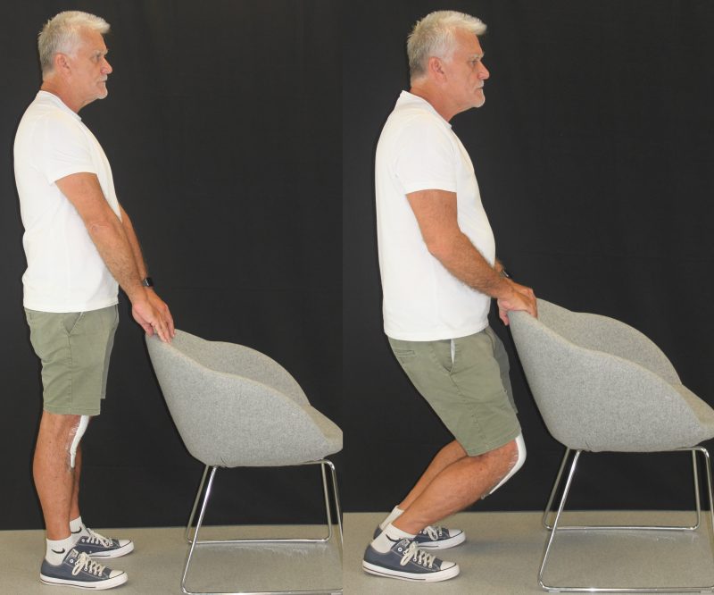 man standing in front of a chair performing squats